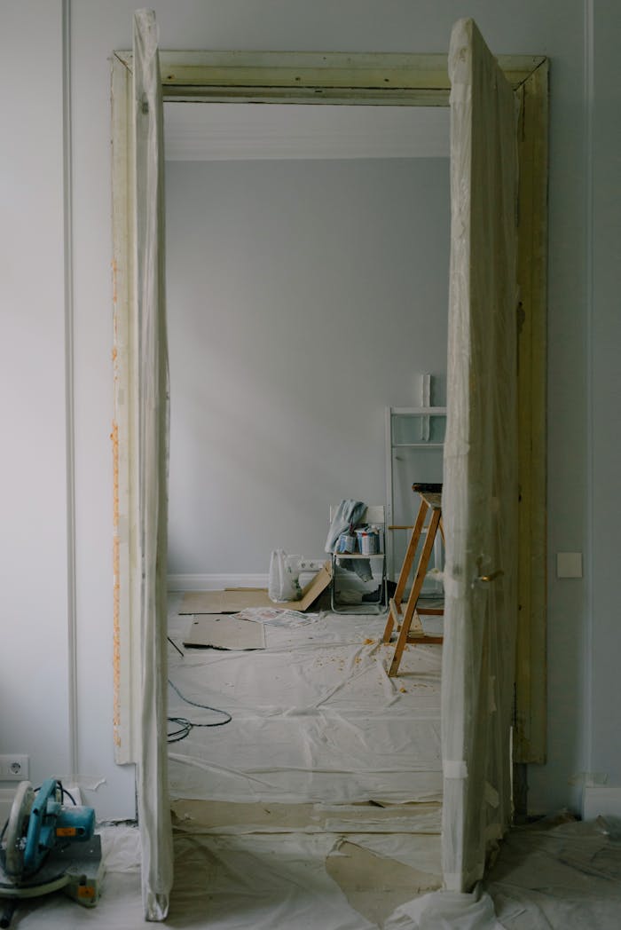 creative-02 View through an open doorway into a room undergoing renovation with tools and materials scattered.