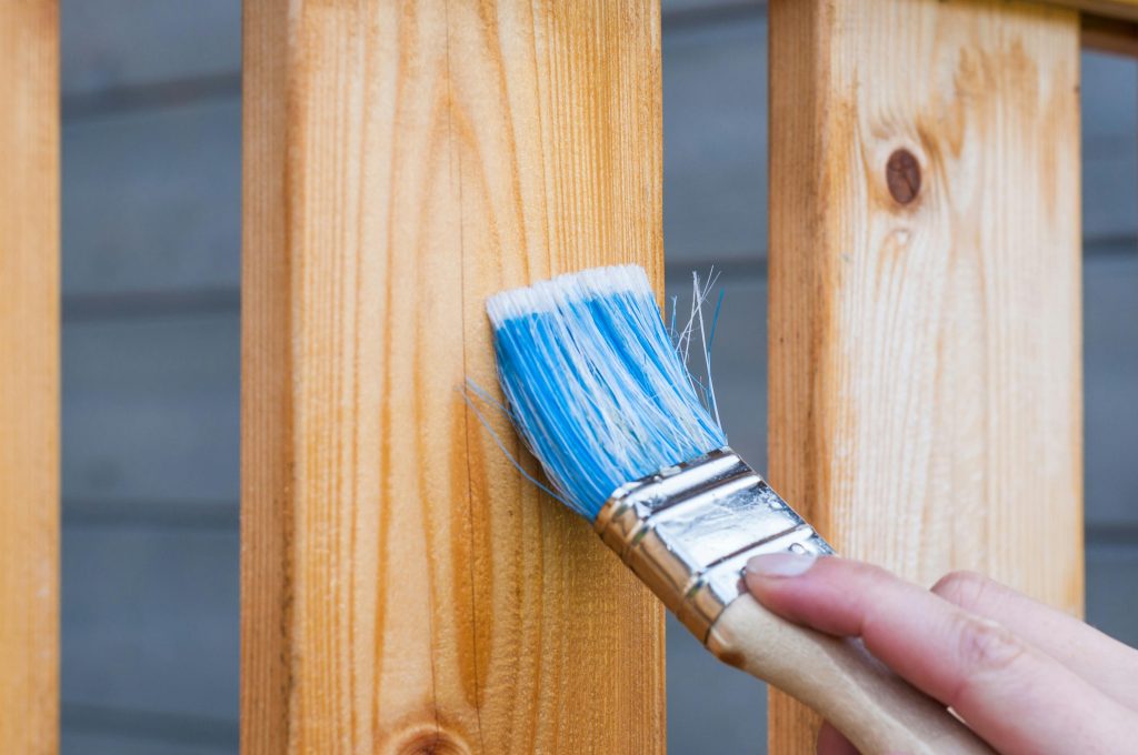 pexels photo 221027 221027 A hand painting a wooden fence plank with a blue paintbrush outdoors. Perfect for DIY and renovation themes.