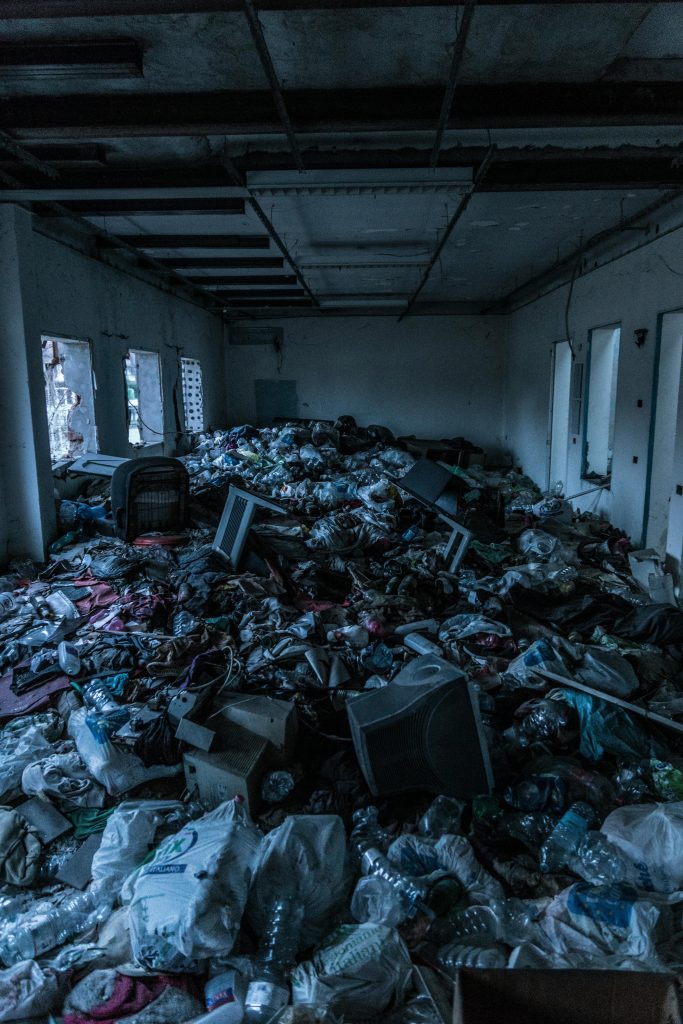 pexels photo 938044 938044 Decrepit indoor room cluttered with heaps of garbage and waste materials.