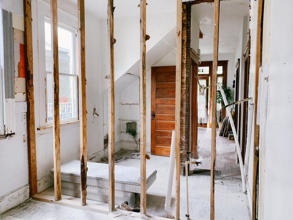 renovations-in-a-house-4756489 Interior view of a home under renovation with exposed wooden beams and door.